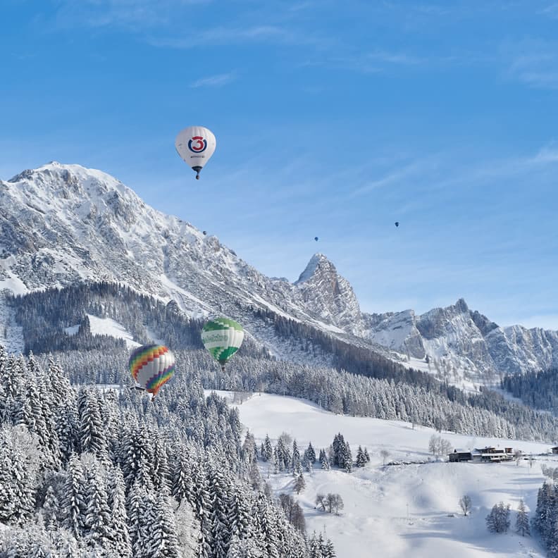 Heißluftballone am Himmel im Winter in Filzmoos